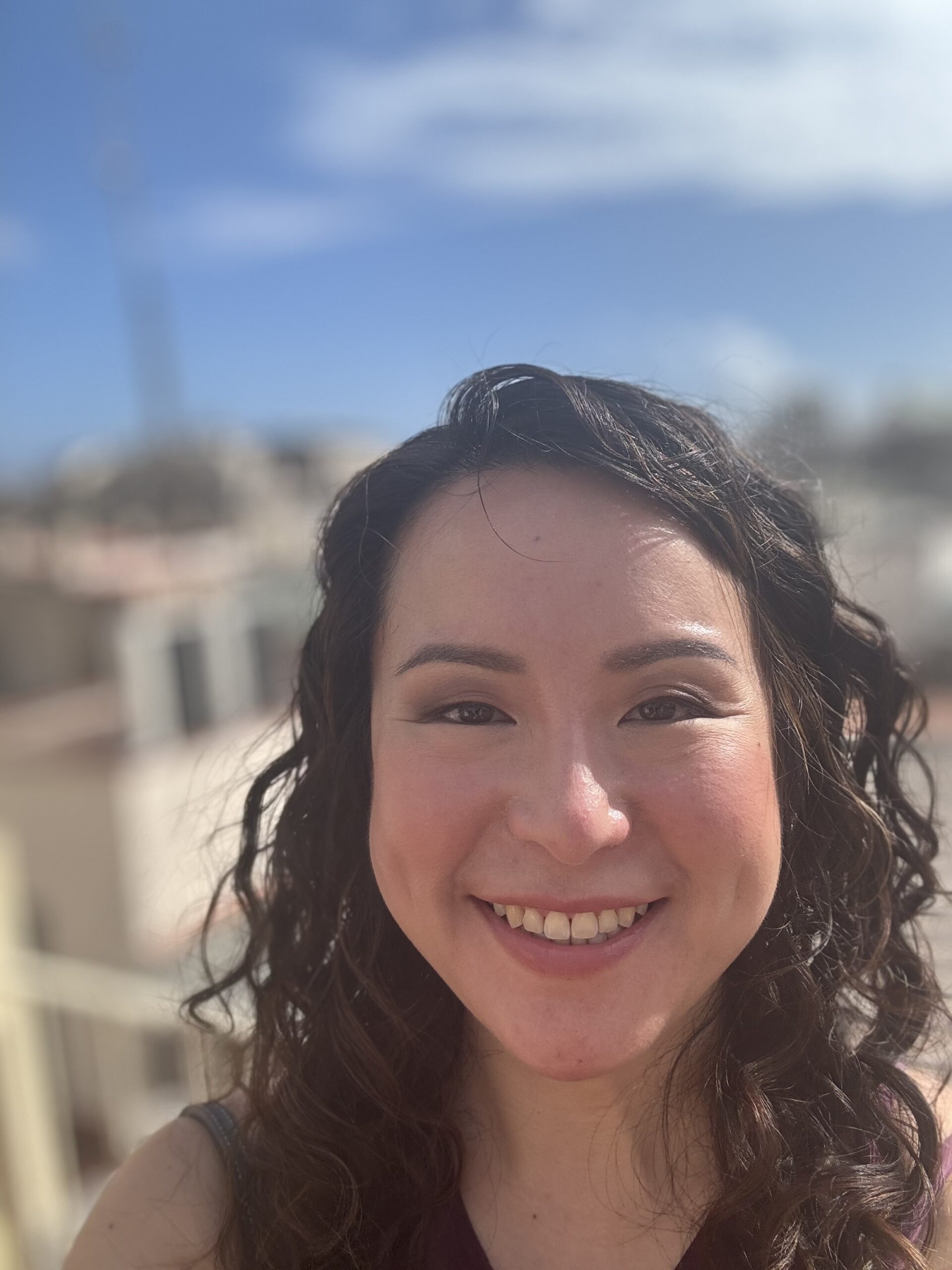 Natalie T smiling beautifully in a blue sky
